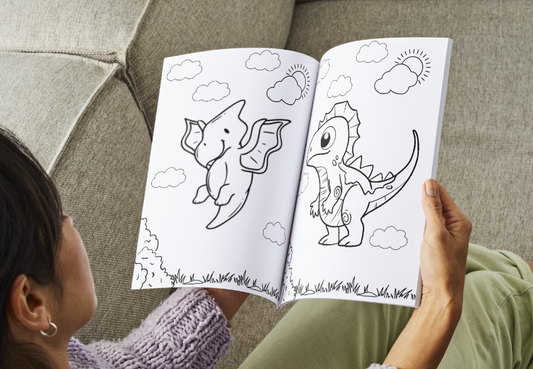 Person coloring a dinosaur in a coloring book on a couch