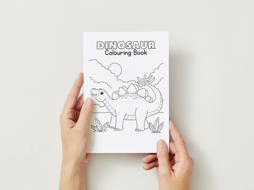 Dinosaur coloring book held by hands on a light background