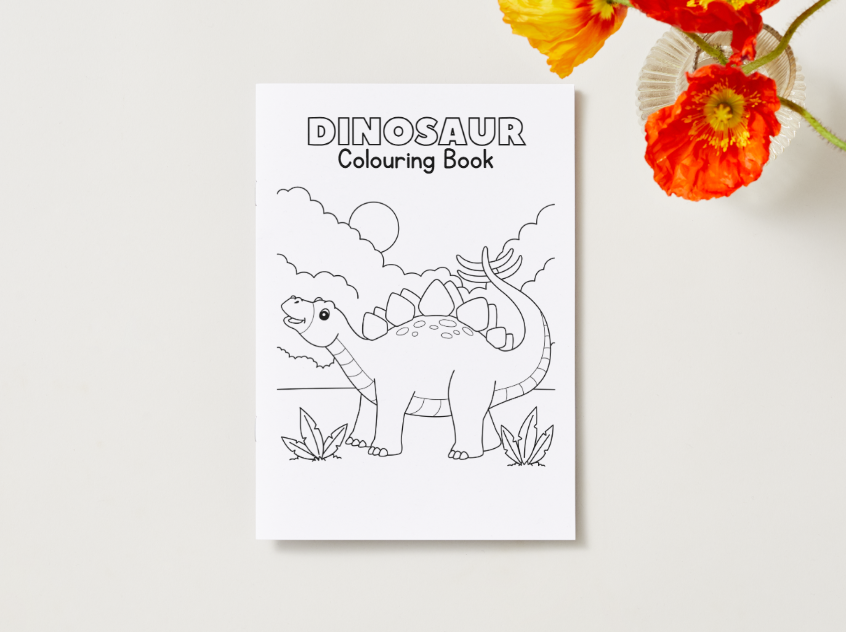 Dinosaur coloring book on a white surface with flowers in the background